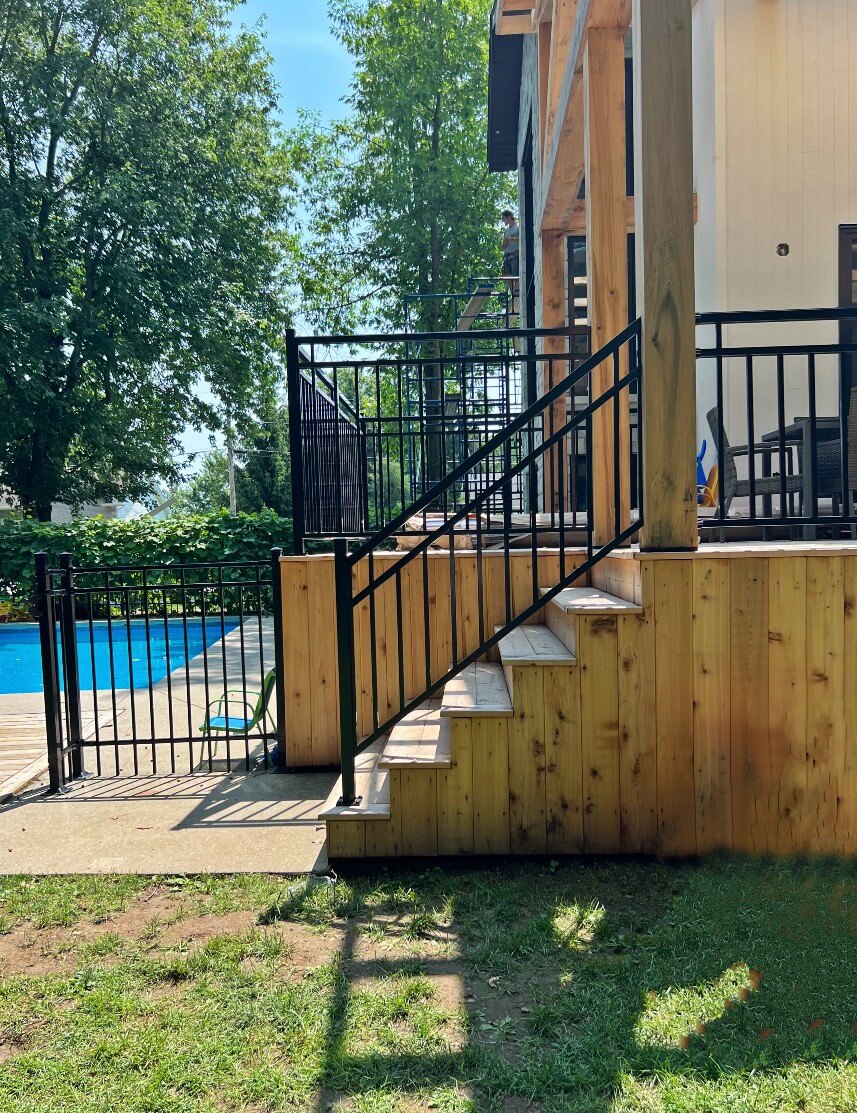 Rampes d'escalier en aluminium noir, avec un patio en bois clair.