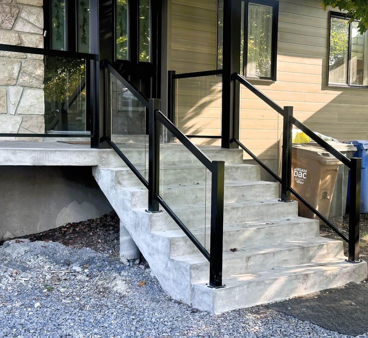 Rampes d'escalier en aluminium noir, avec un patio en bois clair.